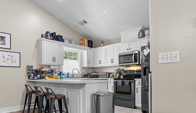 kitchen featuring a breakfast bar, appliances with stainless steel finishes, a peninsula, white cabinetry, and visible vents