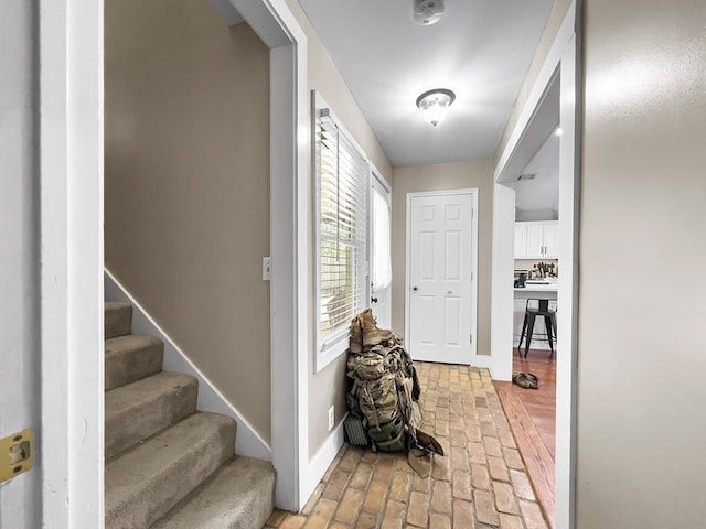 interior space featuring baseboards, stairs, and brick floor