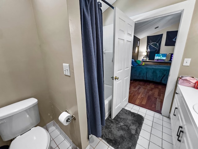 bathroom featuring toilet, vanity, ensuite bath, lofted ceiling, and tile patterned flooring