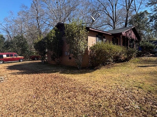 view of property exterior featuring brick siding and a lawn