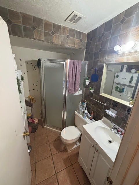 bathroom with tile patterned flooring, visible vents, tile walls, and a shower stall