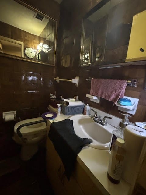 half bathroom featuring visible vents, vanity, and toilet