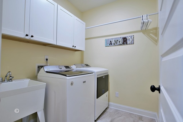 clothes washing area with washing machine and clothes dryer, light colored carpet, cabinets, and sink