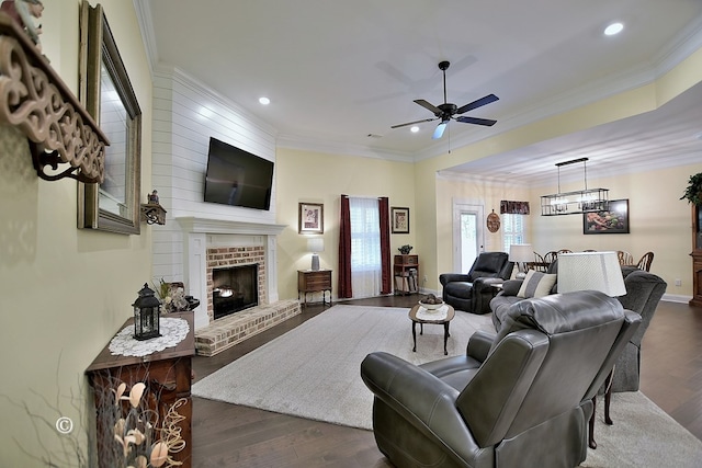 living room featuring ceiling fan, ornamental molding, dark wood-type flooring, and a brick fireplace