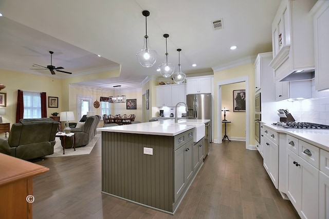 kitchen with ceiling fan, dark wood-type flooring, pendant lighting, white cabinetry, and an island with sink