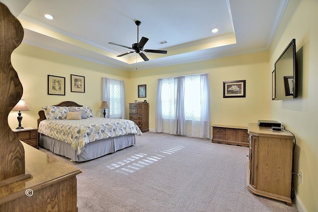 carpeted bedroom with a tray ceiling, ceiling fan, and crown molding