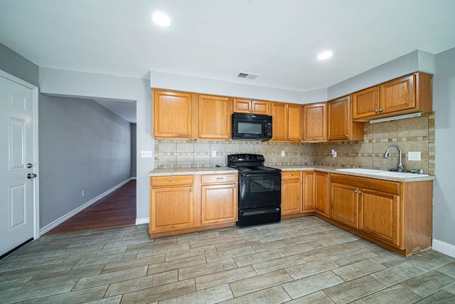 kitchen with tile countertops, visible vents, a sink, decorative backsplash, and black appliances