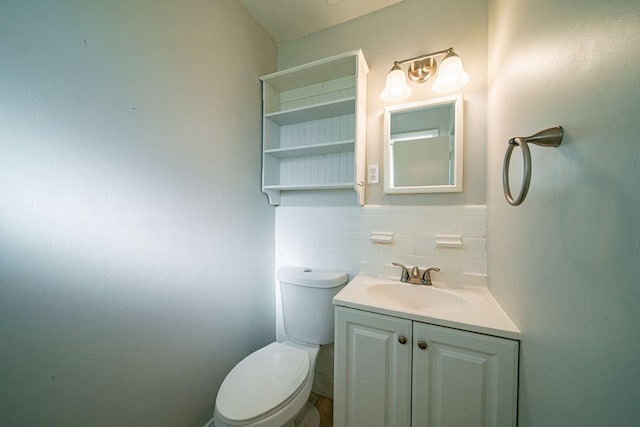 half bathroom featuring tile walls, toilet, and vanity