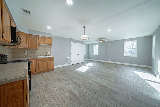 kitchen featuring black appliances, tile countertops, tasteful backsplash, and visible vents