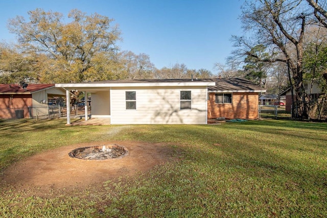 back of house with brick siding, an outdoor fire pit, a yard, and fence