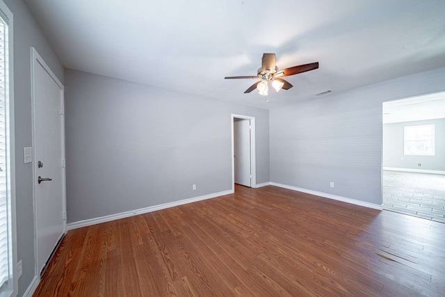 empty room with visible vents, baseboards, wood finished floors, and a ceiling fan