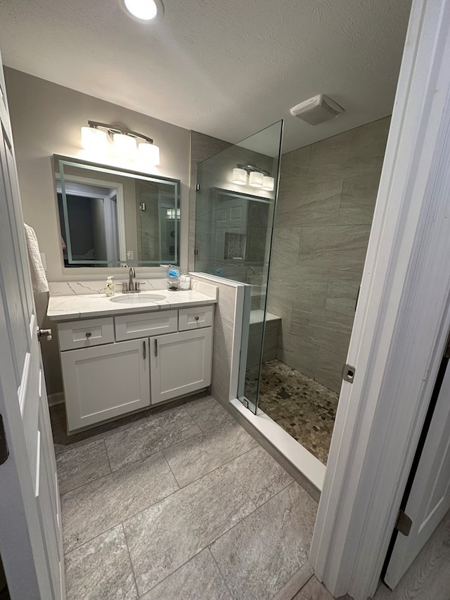 full bathroom with vanity, visible vents, and tiled shower