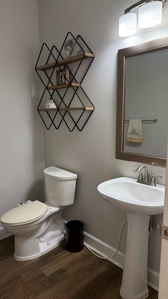 bathroom with a sink, baseboards, toilet, and wood finished floors