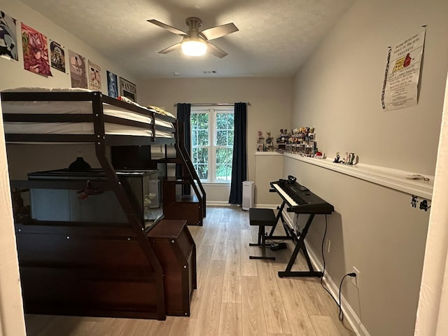 bedroom featuring visible vents, baseboards, a textured ceiling, and wood finished floors