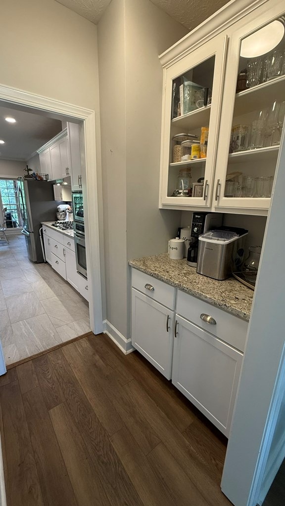 bar featuring baseboards, stainless steel appliances, and dark wood finished floors