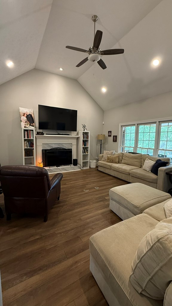 living room with wood finished floors, lofted ceiling, a fireplace, recessed lighting, and a ceiling fan
