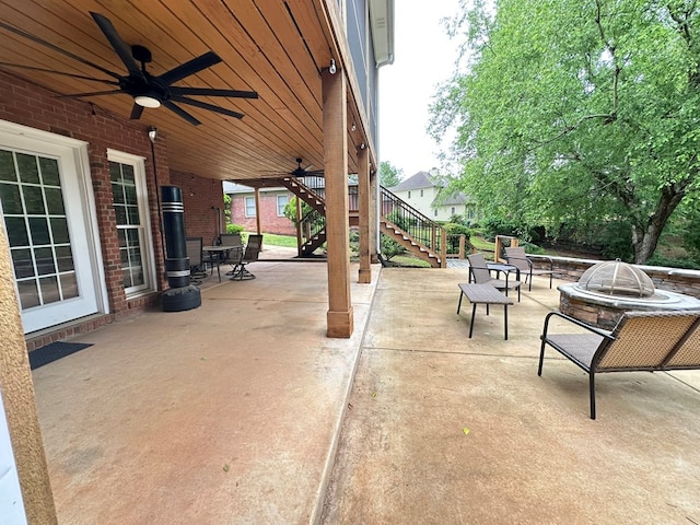 view of patio featuring a ceiling fan, stairs, and an outdoor fire pit