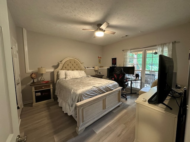 bedroom with ceiling fan, a textured ceiling, visible vents, light wood-type flooring, and access to outside
