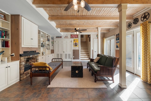 living room with ornate columns, a fireplace, ceiling fan, wooden ceiling, and beamed ceiling