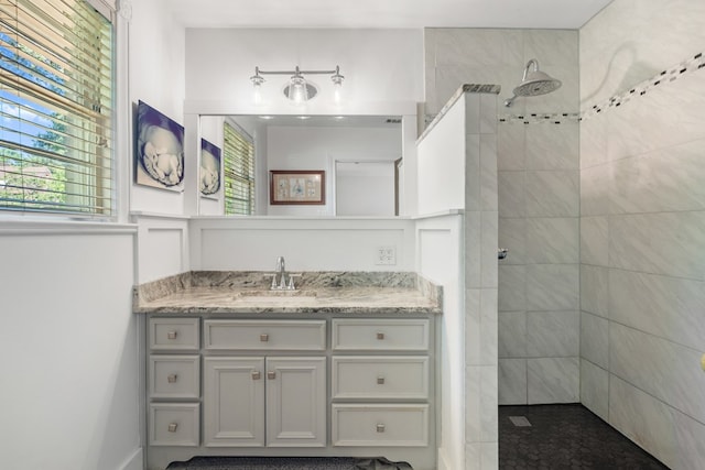 bathroom featuring tiled shower and vanity