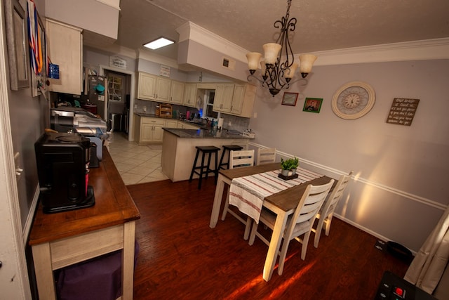 dining room with visible vents, ornamental molding, wood finished floors, a textured ceiling, and a notable chandelier