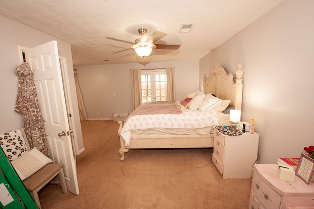 bedroom featuring a ceiling fan, visible vents, a textured ceiling, and light colored carpet