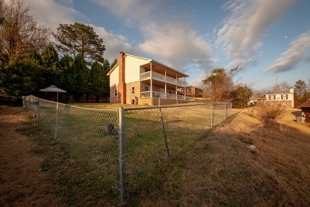 back of property featuring a chimney, fence, and a balcony