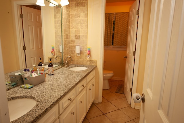 full bath featuring double vanity, a sink, toilet, and tile patterned floors