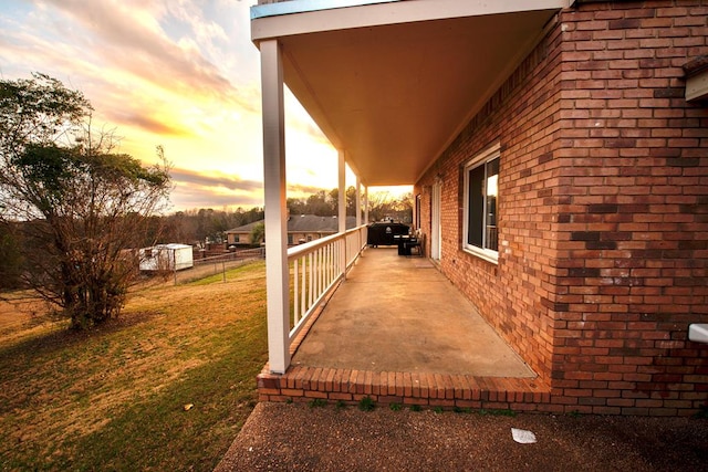 property exterior at dusk with brick siding and a lawn