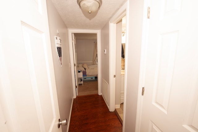 hallway featuring a textured ceiling, baseboards, and wood finished floors