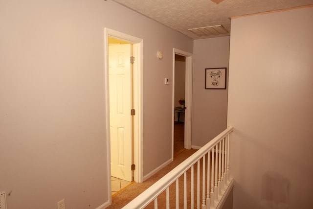 corridor featuring visible vents, a textured ceiling, and baseboards