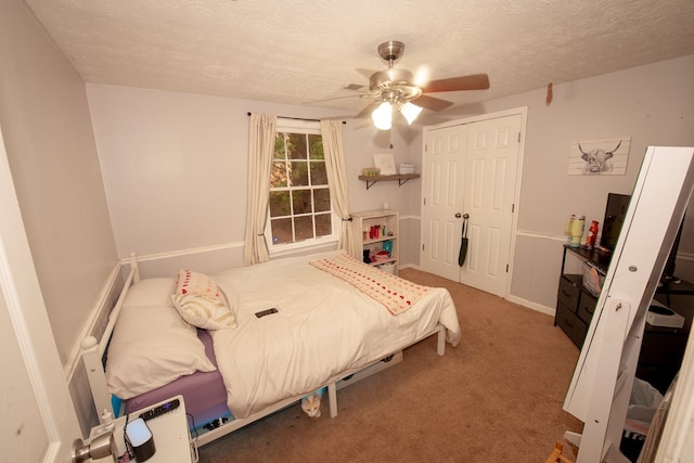 carpeted bedroom with a textured ceiling, ceiling fan, and a closet