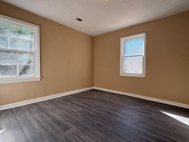 spare room with a textured ceiling and dark hardwood / wood-style floors