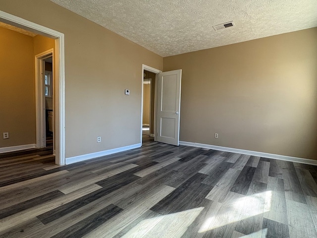 unfurnished room featuring dark hardwood / wood-style flooring and a textured ceiling