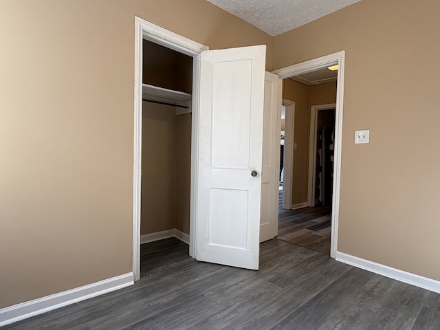 unfurnished bedroom with dark wood-type flooring, a textured ceiling, and a closet