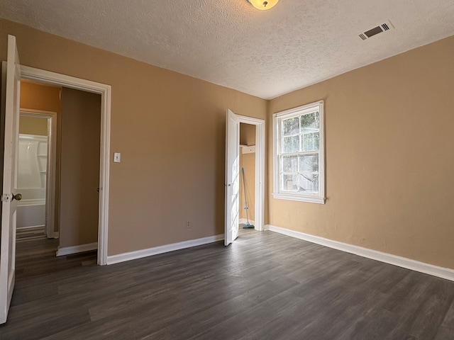 unfurnished room with a textured ceiling and dark wood-type flooring