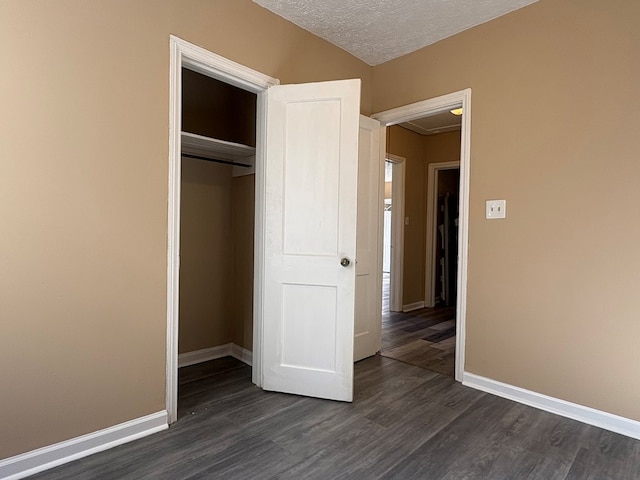 unfurnished bedroom with dark wood-type flooring, a textured ceiling, and a closet