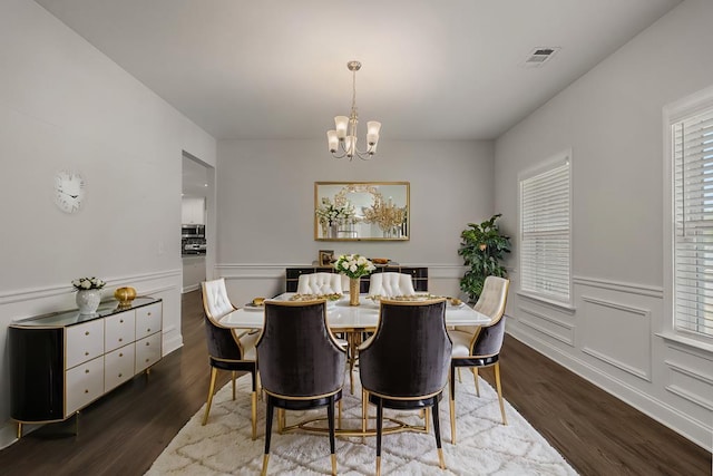 dining space with dark hardwood / wood-style floors and an inviting chandelier