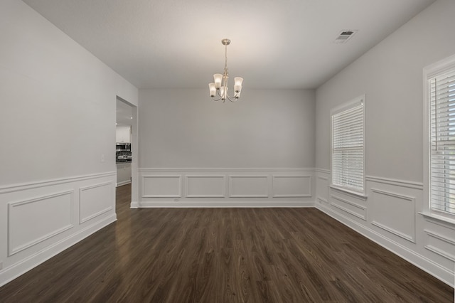 empty room featuring dark hardwood / wood-style flooring and a chandelier