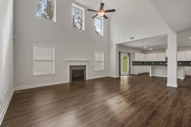 unfurnished living room with dark hardwood / wood-style floors, ceiling fan, and a towering ceiling