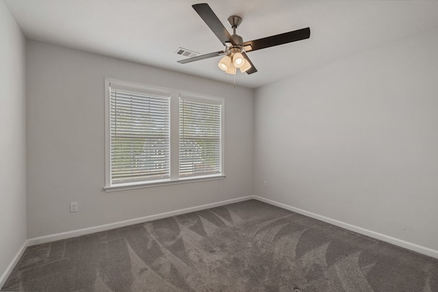 spare room featuring dark carpet and ceiling fan