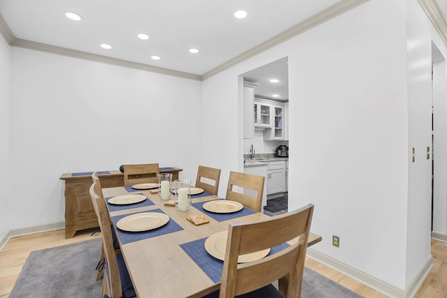 dining area featuring crown molding, sink, and light wood-type flooring