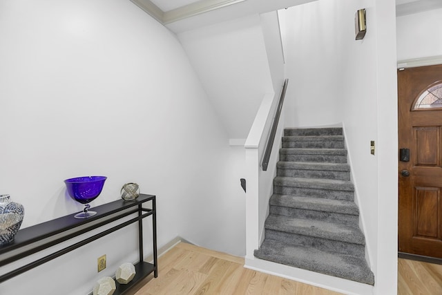 stairs featuring hardwood / wood-style floors and crown molding