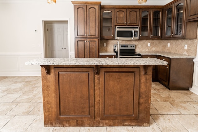 144 Lee Road 2083, Phenix City, AL 36870 - kitchen with stainless steel appliances, a center island, tasteful backsplash, light stone counters, and wainscoting