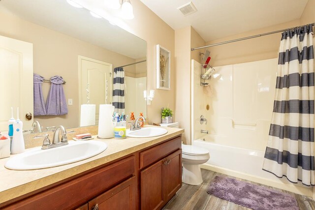 full bathroom featuring vanity, hardwood / wood-style flooring, shower / bath combination with curtain, and toilet