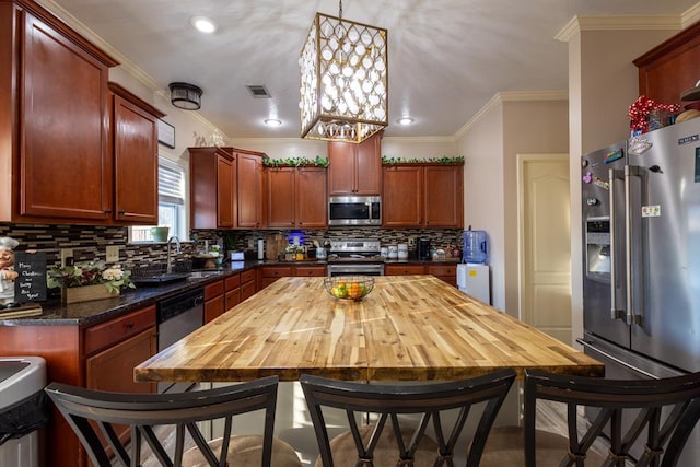 kitchen featuring pendant lighting, sink, crown molding, wooden counters, and stainless steel appliances