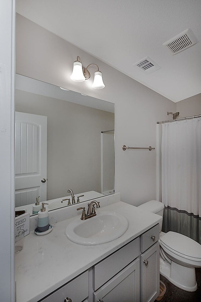 bathroom featuring curtained shower, vanity, and toilet