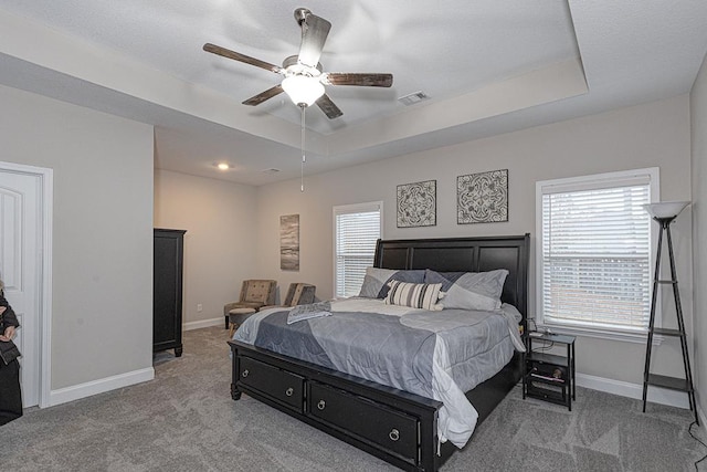 bedroom with a tray ceiling, ceiling fan, and light colored carpet