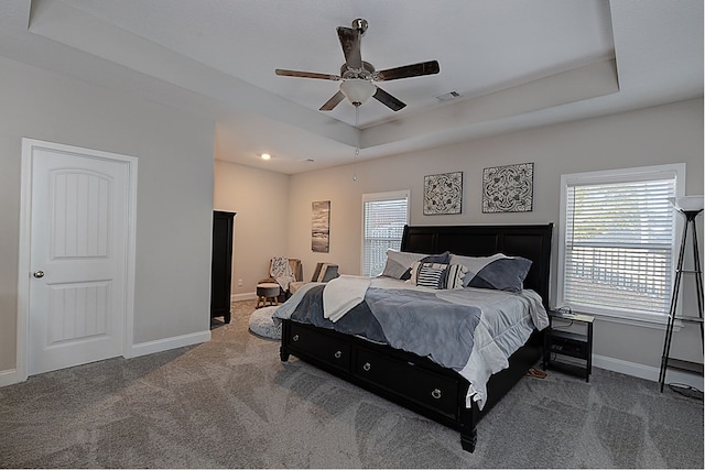 bedroom with dark carpet, a raised ceiling, and ceiling fan