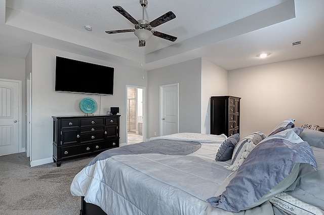 bedroom with carpet floors, ensuite bathroom, a raised ceiling, and ceiling fan